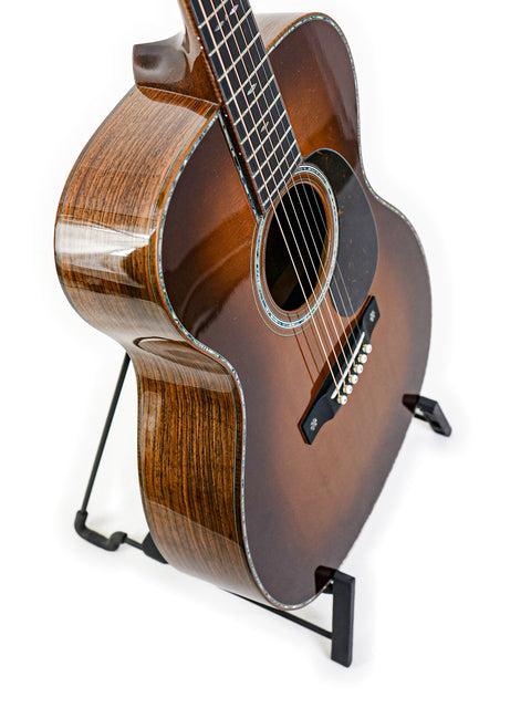 A 2019 Martin Custom Shop 000-42 guitar in Guatemalan Rosewood, elegantly positioned on a stand with a white backdrop.