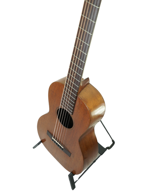 A 1928 Martin 2-17 Flat Top guitar with a wooden body, elegantly positioned on a stand, representing vintage artistry.