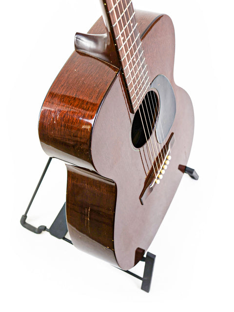 A 1954 Vintage Martin 00-17 guitar elegantly displayed on a stand with a pristine white background.