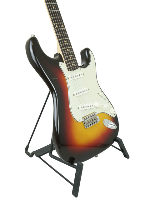 A 1961 USA Fender Stratocaster guitar on a stand, featuring a beautiful sunburst finish that highlights its vintage charm.