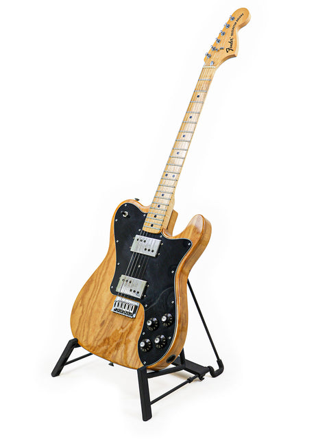 A 1973 Vintage Fender Telecaster Deluxe guitar elegantly displayed on a stand with a bright white backdrop.