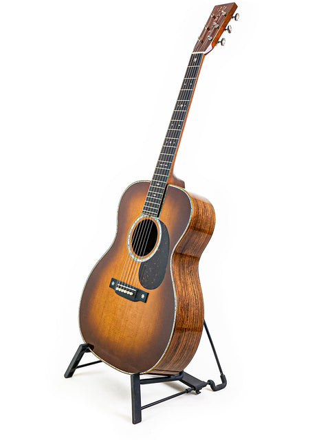 A 2019 Martin Custom Shop 000-42 guitar in Guatemalan Rosewood, elegantly positioned on a stand with a white backdrop.