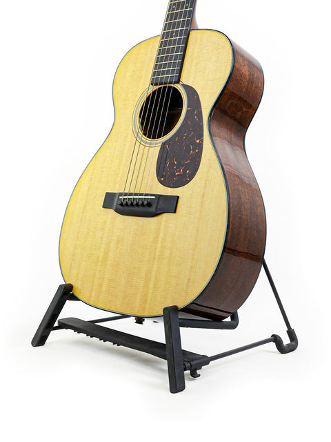 A Martin 0-18 guitar displayed on a stand, featuring a pristine white background that highlights its classic beauty.