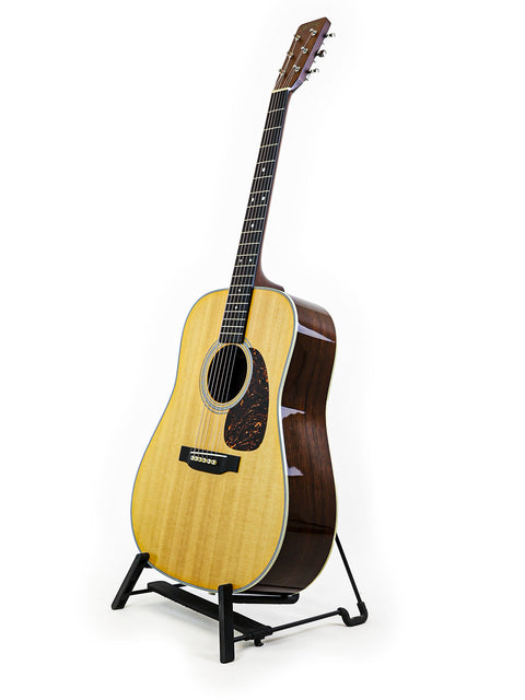 A Martin D-28 CFM IV guitar on a stand against a clean white background, showcasing its limited edition design.