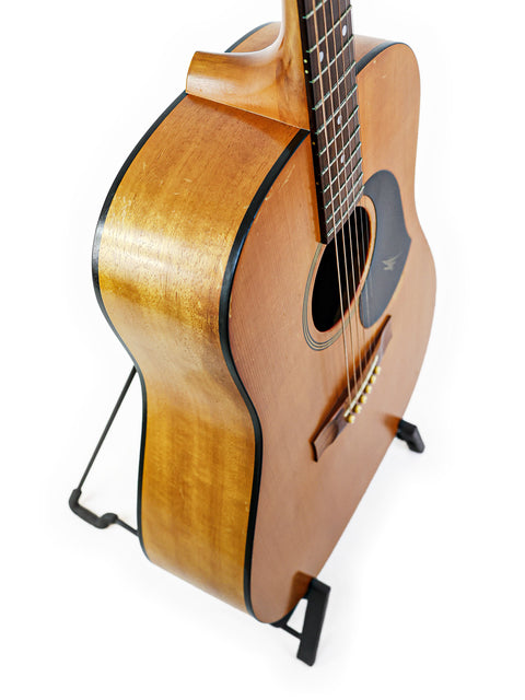 A Maton M225 guitar, made in Australia in 1996, resting on a stand with a bright white background.