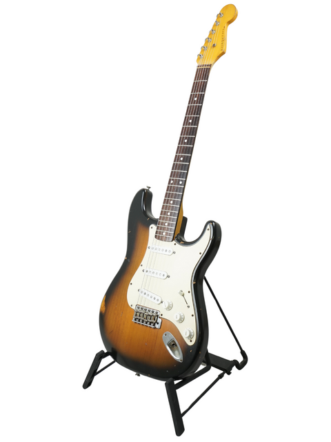 A Nash S63 Stratocaster Relic guitar displayed on a stand, set against a bright white background, highlighting its unique relic finish.