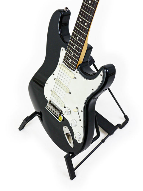 A black 1991 Fender Strat Plus guitar on a stand, set against a simple white background for emphasis.