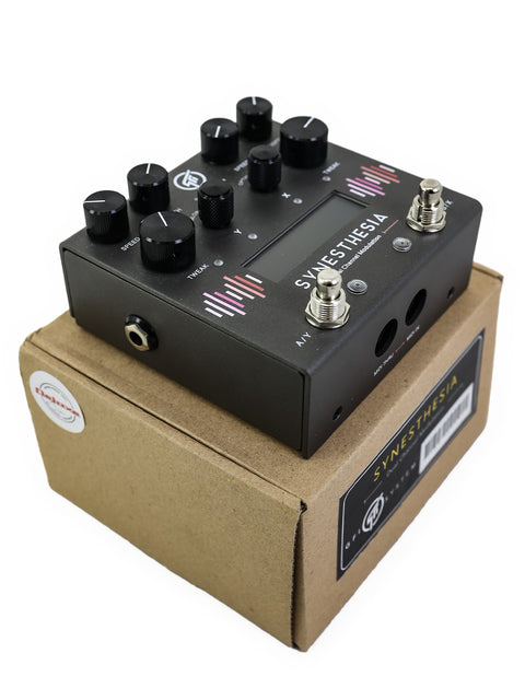 A black modulation pedal is positioned in a cardboard box, marked as GFI System Synesthesia Dual Channel Modulation, Indonesia.
