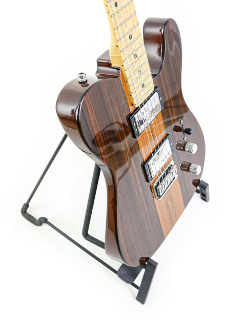 A brown electric guitar on a black stand against a white background.