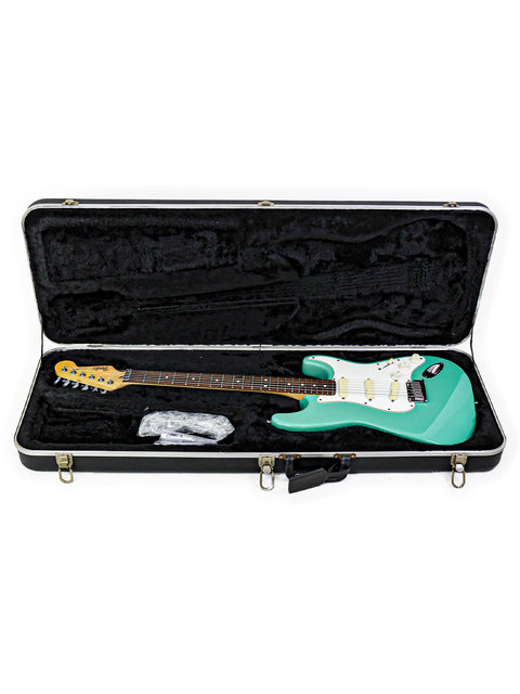 A green guitar, the Fender Strat Plus Deluxe from 1989, housed in a case on a white background.