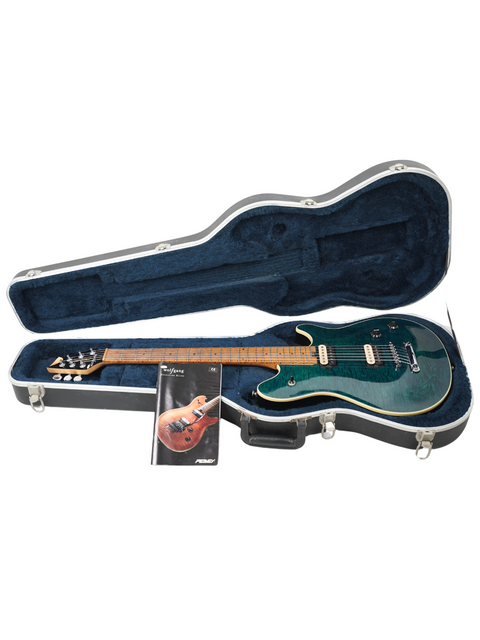 A green guitar, the Peavey EVH Wolfgang Standard Hardtail, sits in its case with a guitar pick placed beside it.