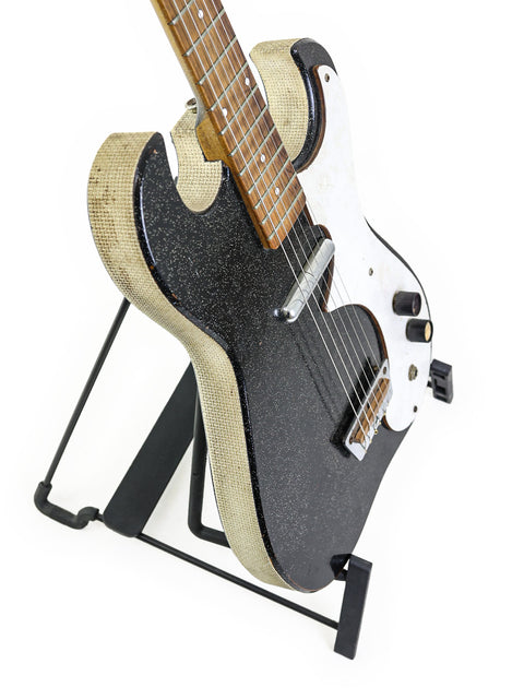 A mid-1960s black Harmony Silvertone 1448 guitar on a stand, showcased with a white background.