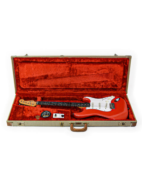 A red vintage Fender AVRI ‘62 Stratocaster guitar securely placed in a red case, representing its 1982 heritage.