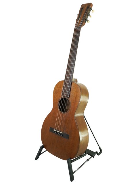 A small vintage Martin 2-17 Flat Top guitar from 1928, elegantly positioned on a stand with a white backdrop.