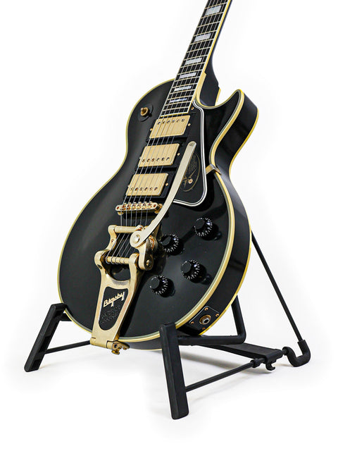 A stunning black and gold Gibson Custom Jimmy Page Les Paul guitar on a stand, representing limited edition craftsmanship.