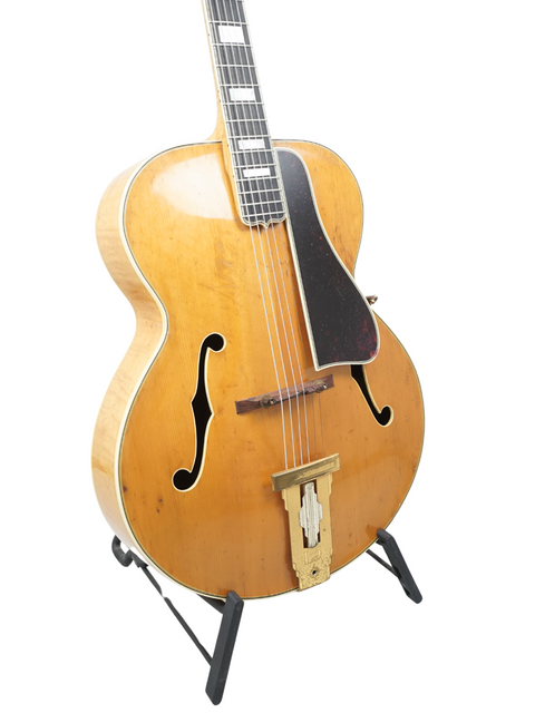 A vintage 1939 Gibson L-5 guitar elegantly positioned on a stand, representing a piece of musical history.