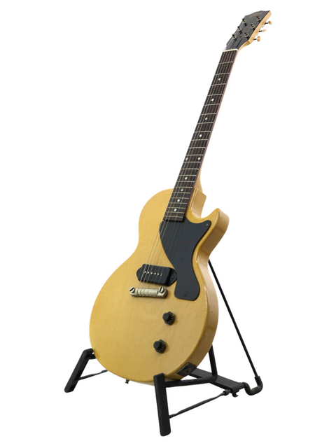 A vintage 1956 Gibson Les Paul Jr guitar in TV Yellow, prominently featured on a stand with a white background.