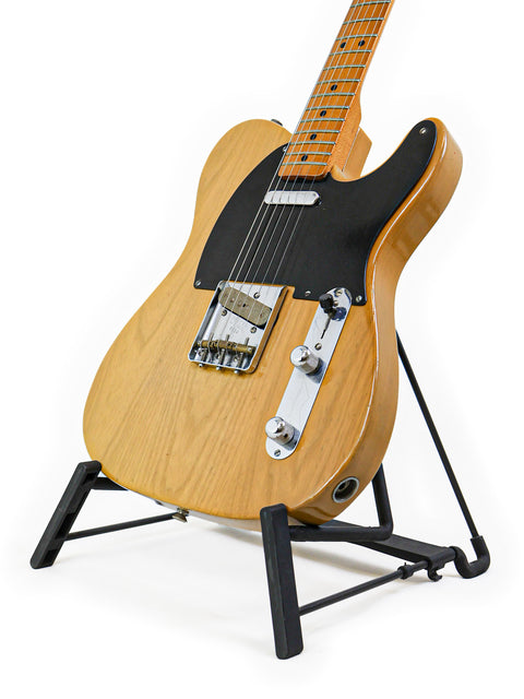 A vintage 1982 Fender AVRI ‘52 Telecaster guitar elegantly positioned on a black stand, ready for a jam session.