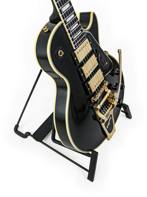 Black Gibson Custom Jimmy Page Les Paul guitar with gold hardware on a stand, part of the 2008 limited edition 467/500.