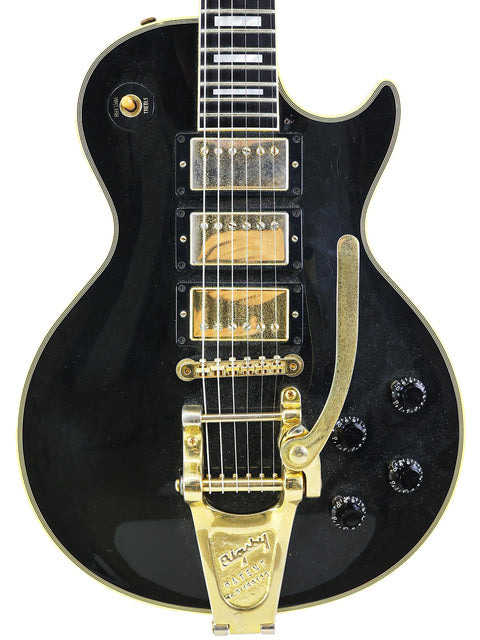 Black electric guitar with gold hardware, a Gibson Custom Shop 1957 Les Paul Custom B3 'Black Beauty' Reissue from 2004.