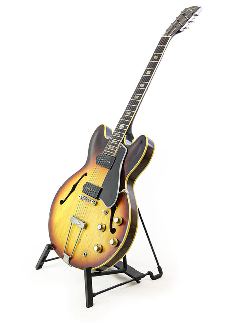 Classic 1964 Gibson ES-330TD guitar on a stand, highlighted by a simple white background for a timeless look.