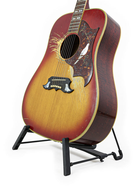 Classic 1968 Vintage Gibson Dove guitar resting on a stand, highlighted by a simple white background.