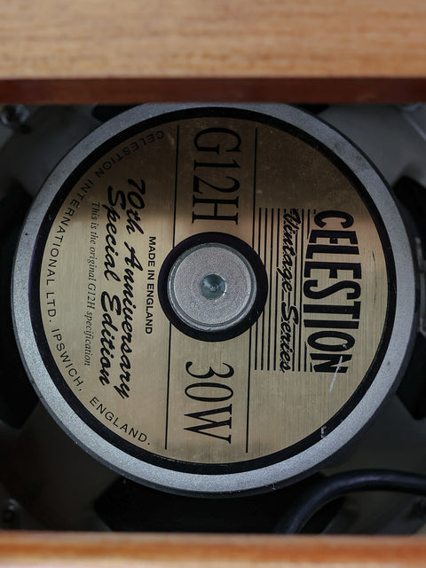 Close-up of a Celestion Vintage 30 speaker inside a wooden cabinet.
