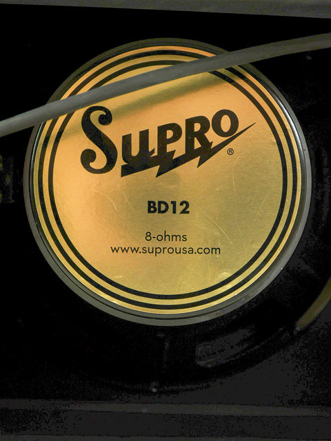 Close-up shot of a black and gold label on a Supro Black Magick 1695T speaker, emphasizing its unique 2015 design.