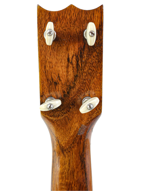 Detailed view of a 1920s Kumalae Ukulele, highlighting the rich texture of its wooden body.