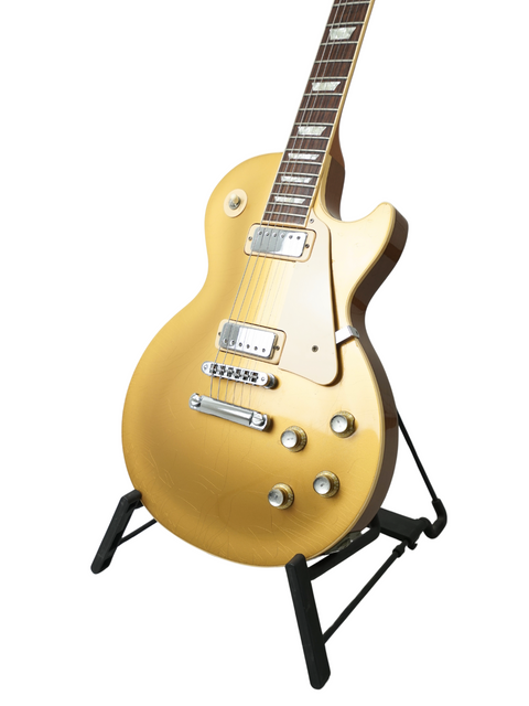 Elegant gold electric guitar on a stand, featuring the Gibson Les Paul Deluxe Limited Edition 30th Anniversary, USA 2000.