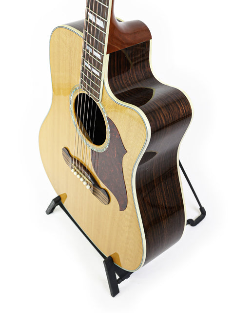 Gibson Songwriter Studio Deluxe EC guitar on a stand against a clean white background, showcasing its elegant design.