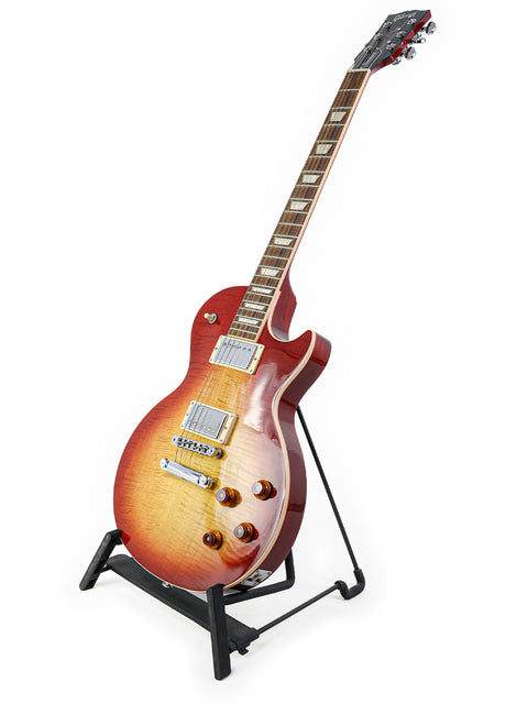 Stunning Gibson Les Paul Standard guitar displayed on a stand, contrasting beautifully with a bold red background.