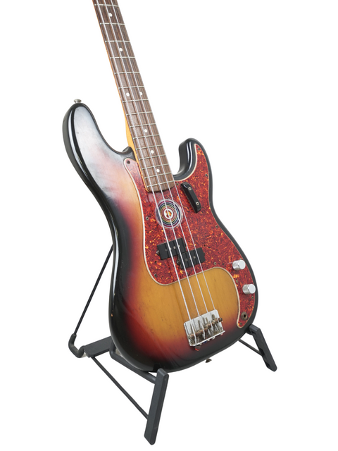 Sunburst electric bass guitar on a black stand against a white background.