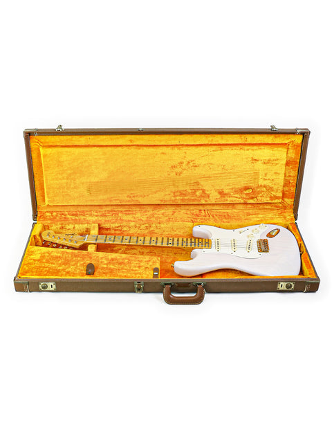 White electric guitar in an open, plush-lined case against a white background.