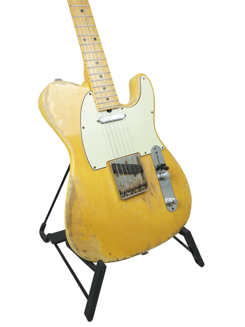 Yellow Suhr Classic T Antique guitar displayed on a stand, set against a bright white backdrop, highlighting its unique design.
