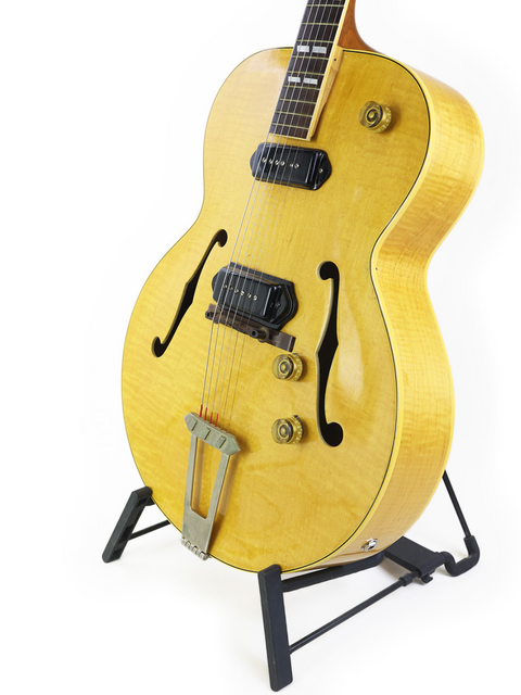 Yellow vintage Gibson ES-300 guitar on a stand, elegantly presented with a bright white background highlighting its features.