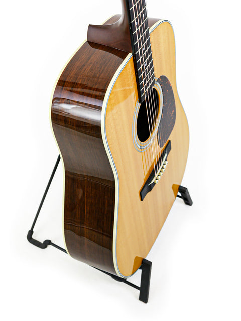 limited edition Martin D-28 CFM IV guitar displayed on a stand, set against a bright white backdrop.