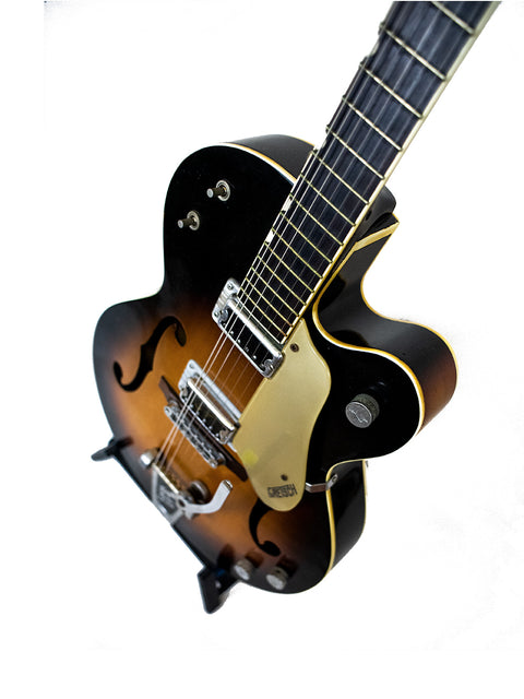 A 1964 Gretsch Double Anniversary 6117 guitar showcasing a black body with a beautiful sunburst finish.