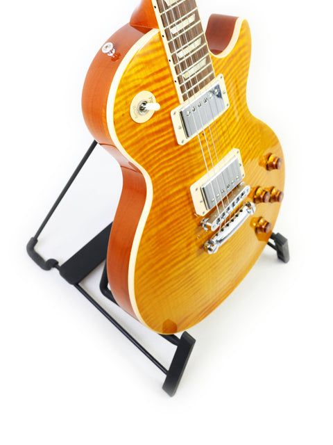 A 2013 Gibson Les Paul Standard guitar displayed on a stand, featuring a striking white background for emphasis.