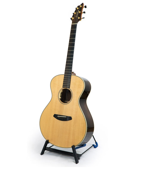 A Breedlove Journey Concert guitar, #22 of 50, elegantly positioned on a stand with a white background highlighting its beauty.