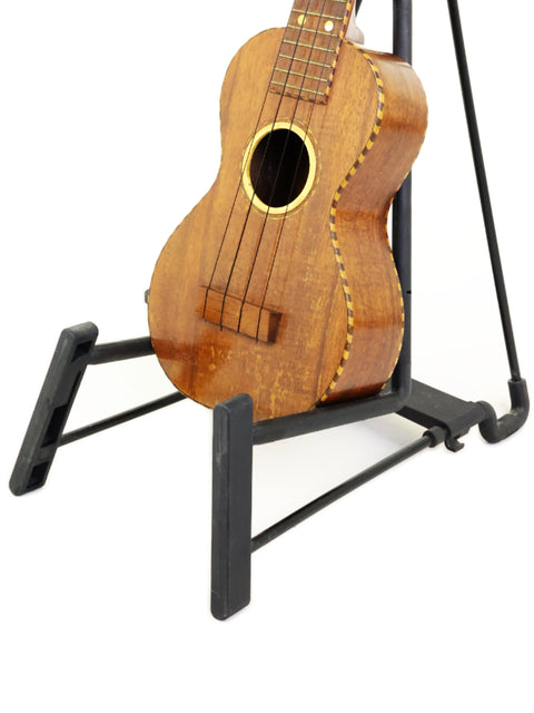 A beautifully crafted 1924 Weissenborn Miami Style 3 Koa Ukulele sits on a stand, ready to inspire with its melodic charm.
