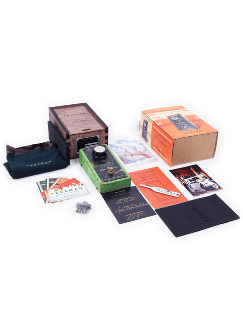 A box showcasing a Trueman 1966 Fuzz Pedal, a book, and several other electronic devices.
