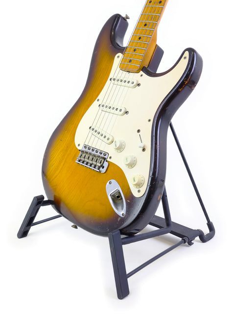 A classic 1954 Vintage Fender Stratocaster guitar elegantly positioned on a stand with a simple white backdrop.