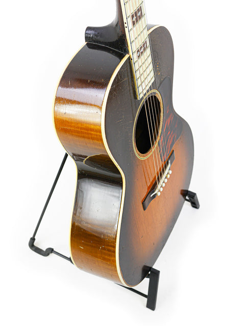 A classic Gibson L-C 'Century of Progress' guitar from 1936, elegantly positioned on a stand with a white background.