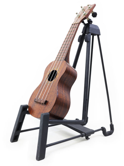 A historic Hawaiian TABU Style 2 "Midget" Koa Ukulele, c. 1917, sitting on a stand, highlighting its unique design.