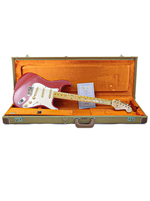 A red Fender Custom Shop ’56 Stratocaster Relic guitar resting in a case, with a stark white background.