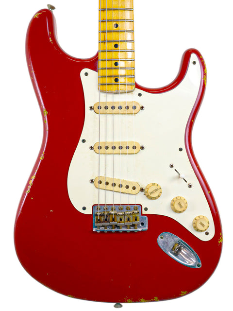 A red Fender Custom Shop ’56 Stratocaster Relic guitar with a white pickguard, showcasing its vintage design and craftsmanship.
