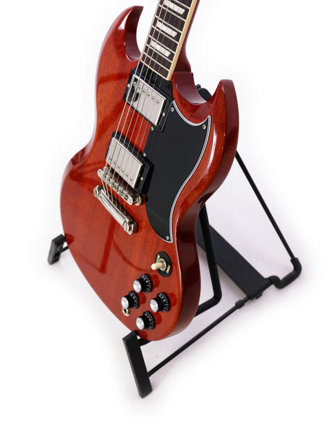 A red Gibson SG Standard ‘61 guitar elegantly positioned on a stand, contrasting beautifully with the white background.