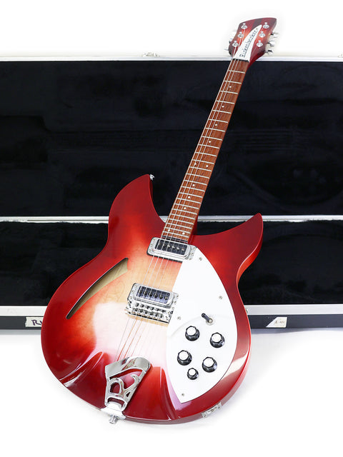 A red Rickenbacker 330 guitar, Fireglo edition from 2006, positioned in its case on the floor, displaying its bold appearance.