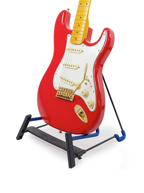 A red StrXX Partscaster guitar from 2012 displayed on a black stand, highlighting its bold color and craftsmanship.